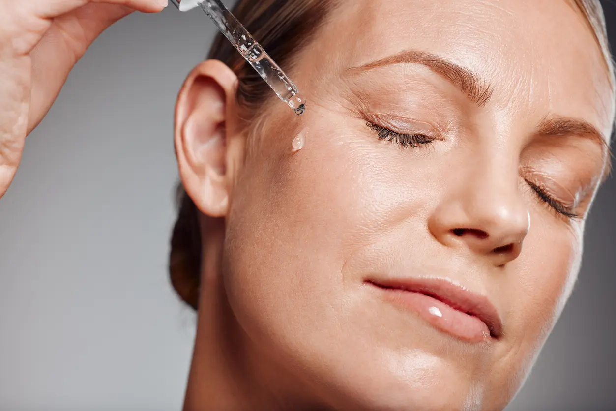 Beautiful mature woman posing with beauty treatment in studio against a grey background