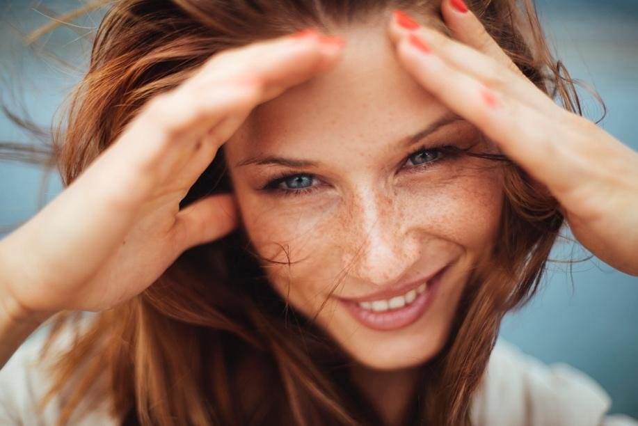 Close-up of a smiling woman with freckles and red hair.