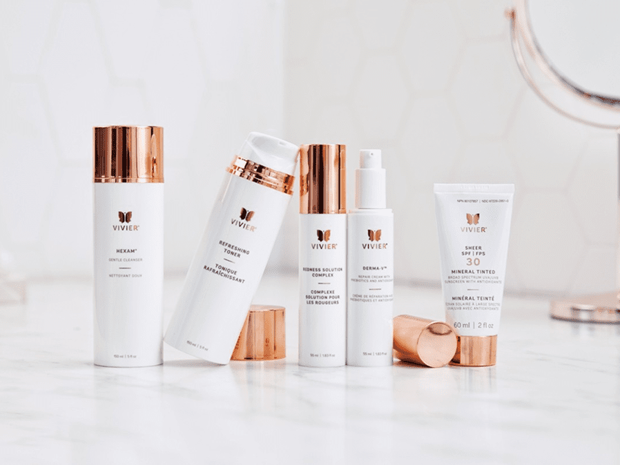 Elegant skincare products with white and rose gold packaging arranged on a marble surface.