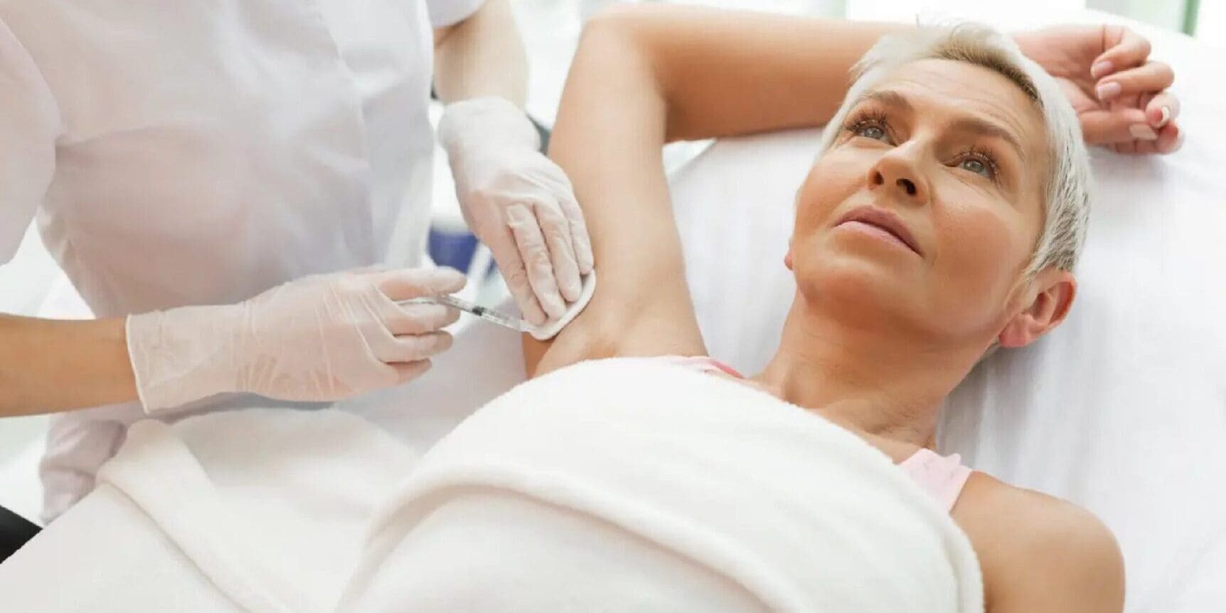 Woman receiving an injection in her underarm during a medical procedure.